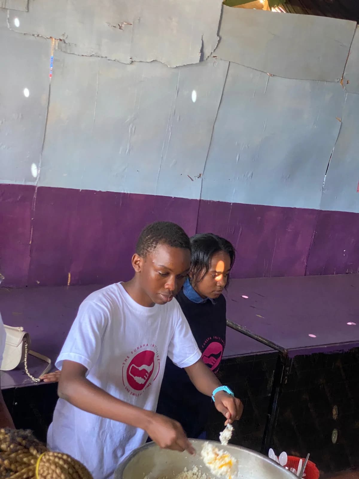 Two Furaha volunteers standing together at a table in the community venue