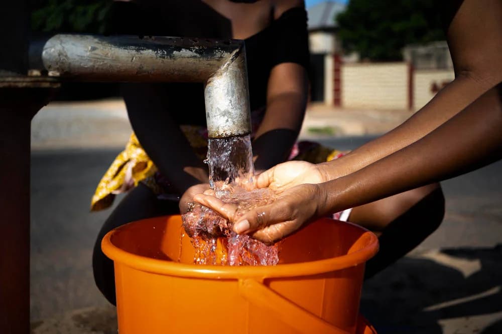 A woman pouring water into a container outdoors